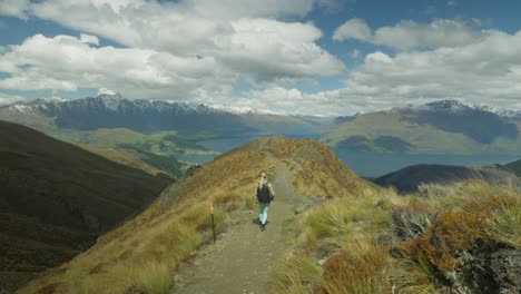 Lone-female-hiker-on-mountain-trail-in-sunny-New-Zealand,-Ben-Lomond