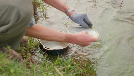 靠近湖水中的男人手洗餐具