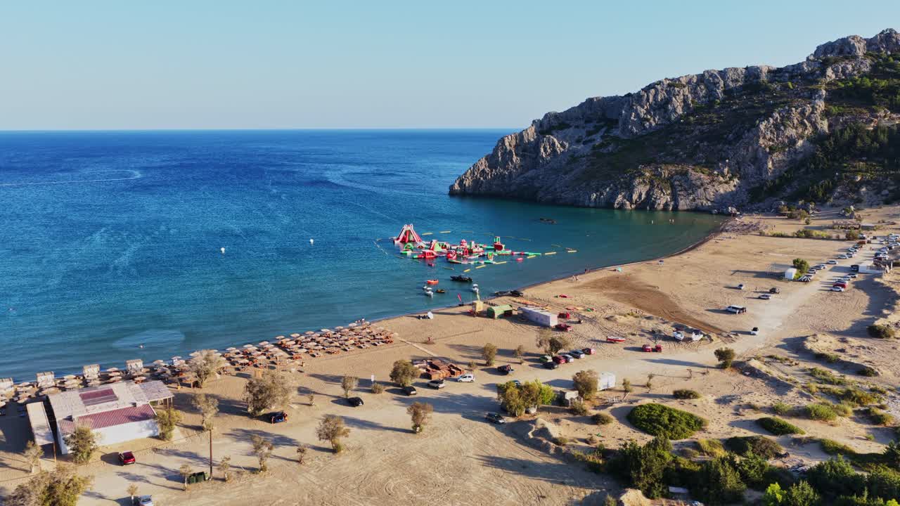 Aerial view of a beautiful beach with an inflatable water park and rocky coastline