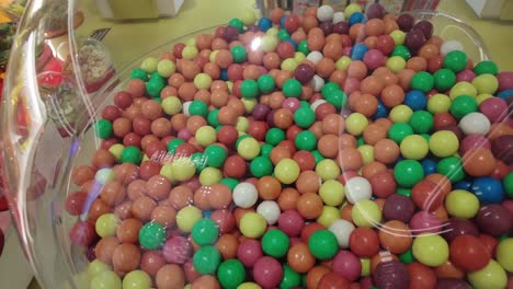 Close-up-lot-of-round-candies-in-multi-ed-in-a-glass-jar-at-shopping-mall-,