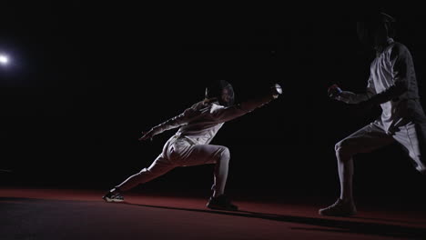 two fencers compete in a match, one is poised to strike while the other is defending