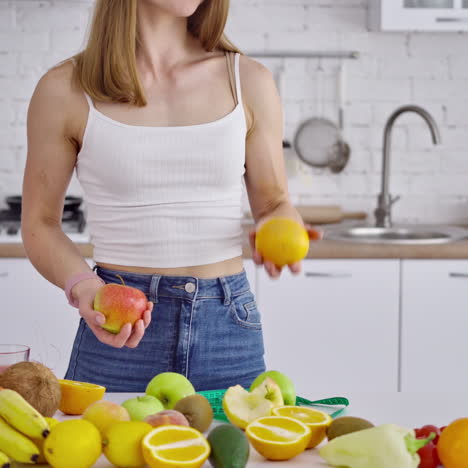 young woman with muscular body in the kitchen. sporty female juggling with fresh fruit on the background of healthy food. healthy diet concept.
