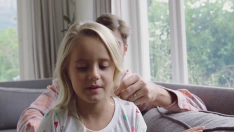 padre peinando el cabello de sus hijas en el sofá en casa 4k