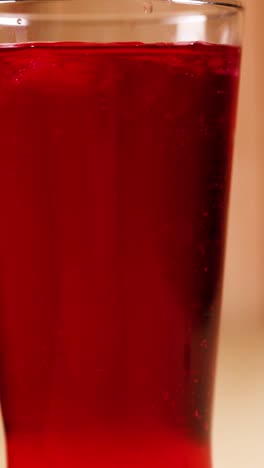 un vaso lleno de refresco rojo