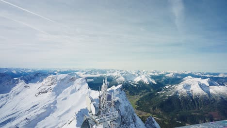 view over the railing and a telephone mast to the green valley below a snowy mountain summit in the alps