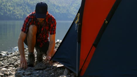Man-preparing-tent-near-riverside-4k