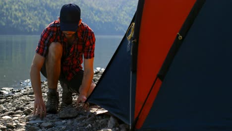 man preparing tent near riverside 4k