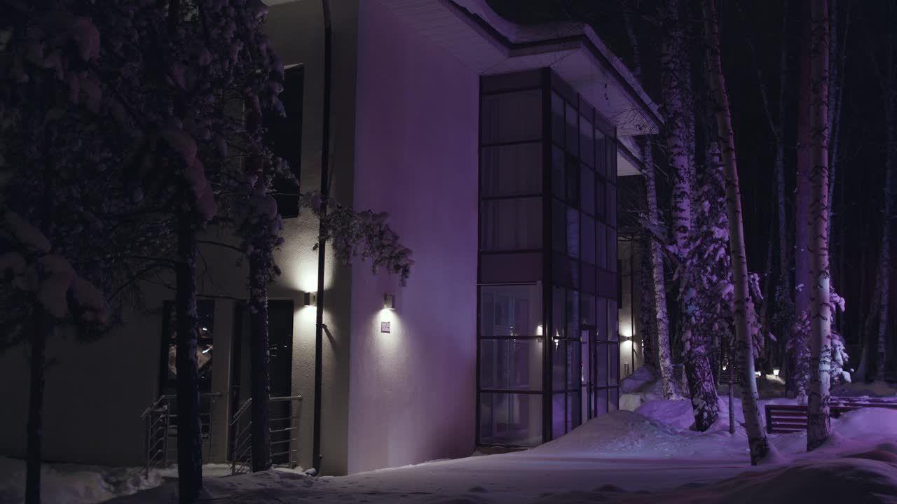 Modernt hus i en snötäckt skog på natten