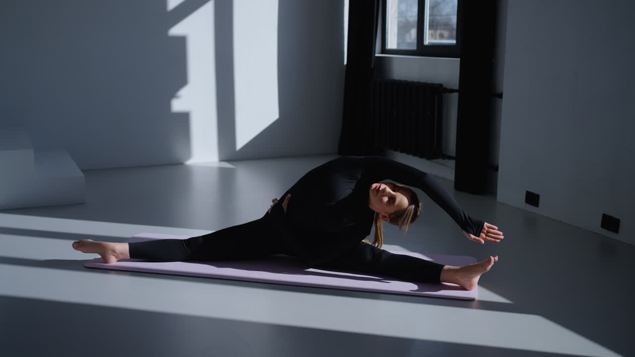 Woman doing a split yoga pose in a studio
