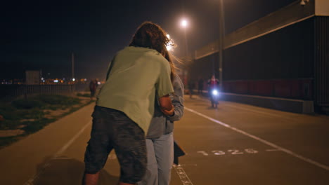 romantic skaters kissing night asphalt road. sport couple enjoying active date