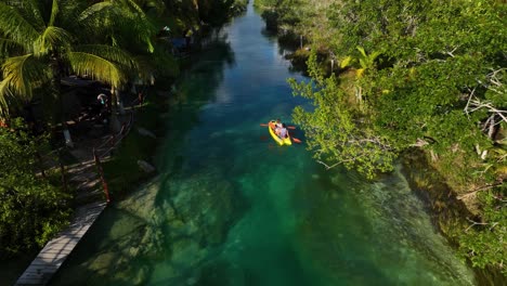 vista aérea rastreando pessoas remando em um canal de floresta tropical, no méxico