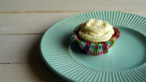 Muffin-cake-with-butter-cream-on-plate-at-wooden-table.-One-cupcake-with-cream