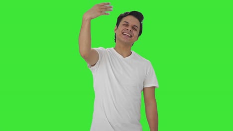 hombre indio feliz señalando y llamando a alguien pantalla verde