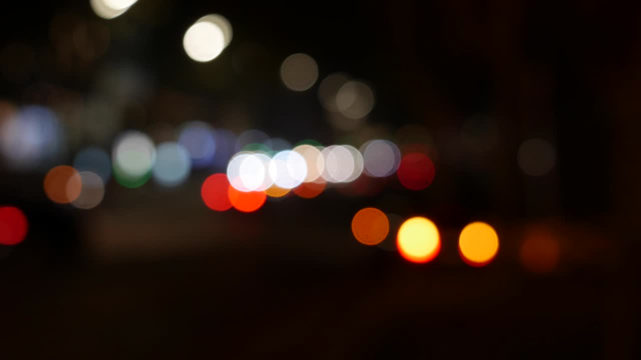 hermoso bokeh brillante en el fondo oscuro borroso por la noche. el redondo bokeh colorido brilla de las luces de los coches en la calle de la ciudad. fuera de foco con borroso. luces de la ciudad sin enfoque. bokeh de tráfico. concepto abstracto