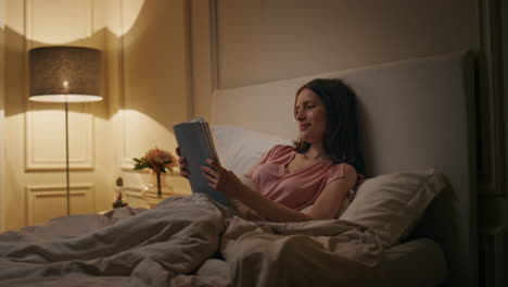 peaceful woman reading book in evening home. smiling reader enjoying novel rest