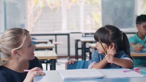 friendly female school teacher and latin schoolgirl talking at class