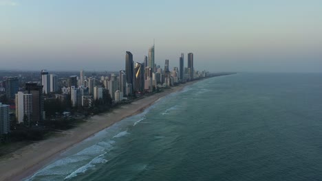 Aerial-view,-drone-flyover-Broadbeach-gold-coast-capturing-long-stretched-sandy-beach-with-waves-crashing-the-shore,-luxury-waterfront-apartments-and-ocean-views-resort-hotels-along-the-coastline