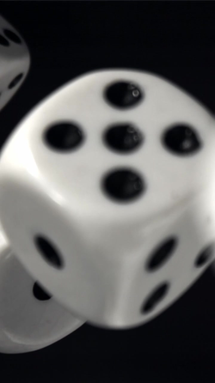 Slowmotion nærbillede af hvide terninger der falder på sort baggrund
