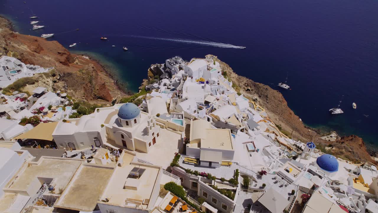 Aerial view of Oia, Santorini, Greece, featuring its iconic white buildings and blue-domed churches overlooking the Aegean Sea