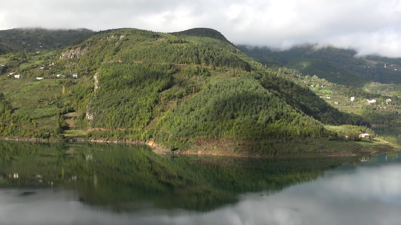 Panoraamanäkymä tyynestä vuoristojärvestä kalankasvattamoineen