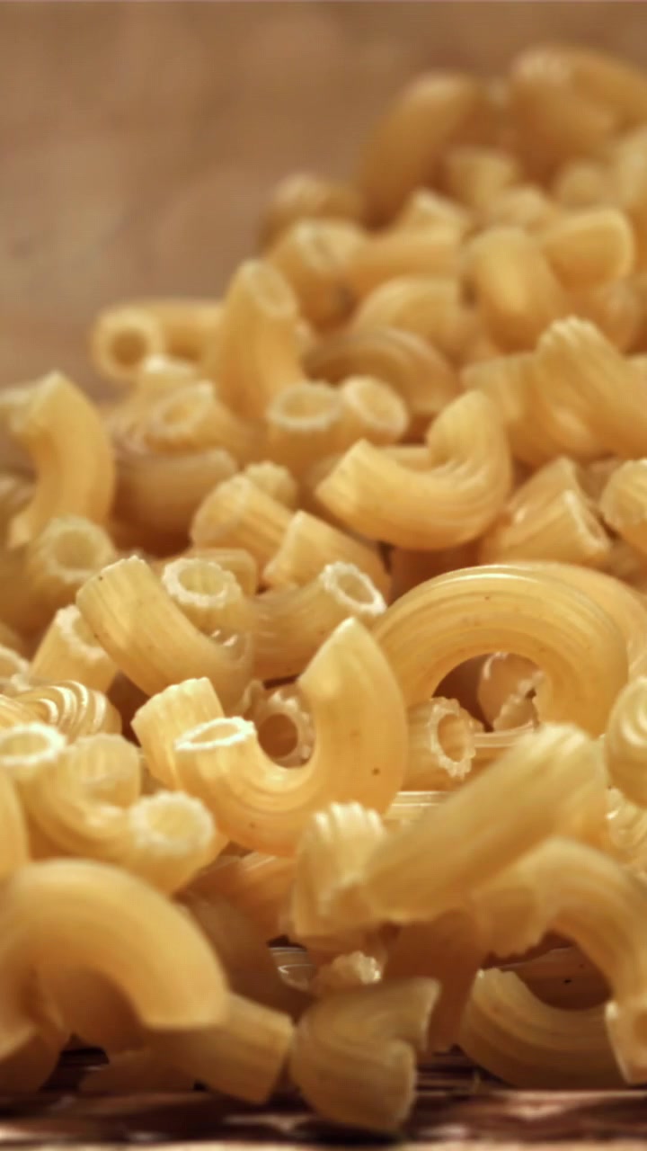 Primo piano di maccheroni secchi che si riversano su una superficie di legno