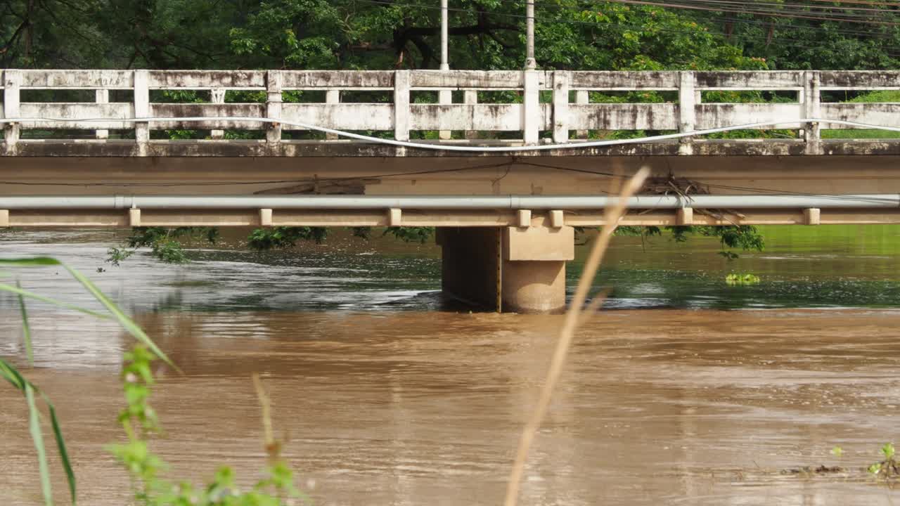 다양한 교통과 빨간 트럭이 있는 다리 아래 흐르는 진흙탕 강