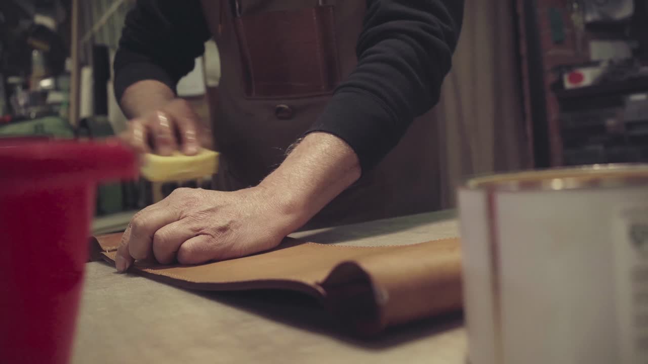un artesano de cuero irreconocible lavando una pieza de cuero recién curtido