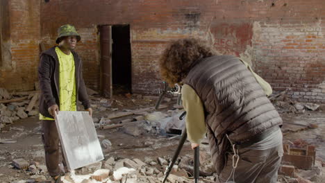 cameraman setting up a camera in a ruined building while another coworker showing a gleaming banner in front of the camera 2