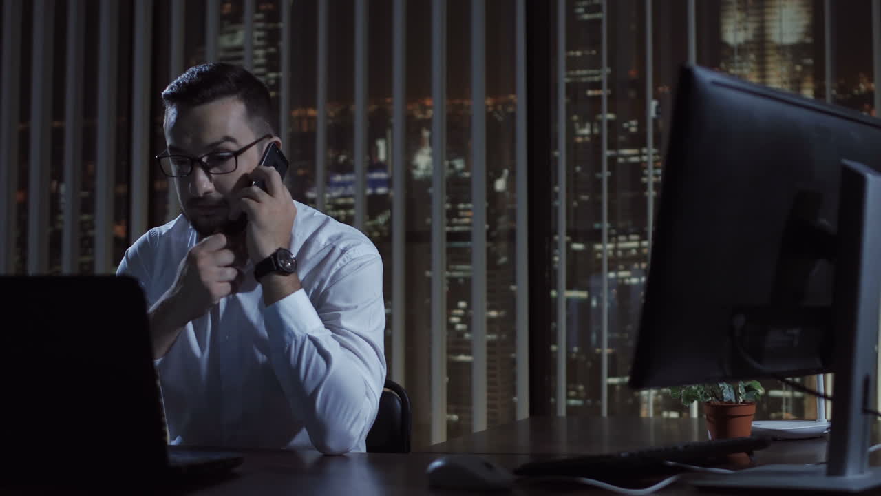 Businessman Working Late at Night in Office, Making a Phone Call