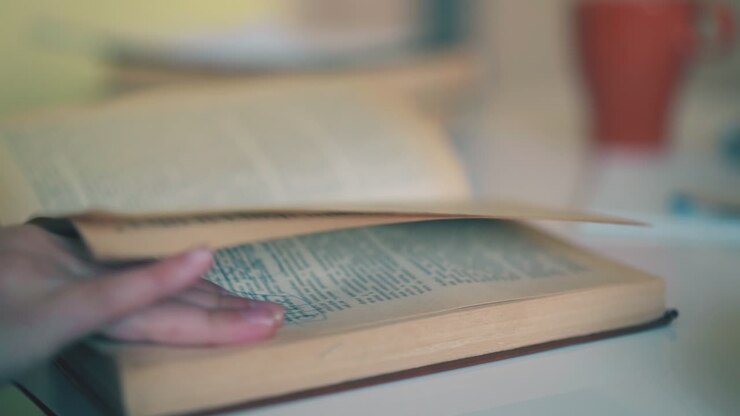 schoolkid turns yellow pages of textbook at table close view
