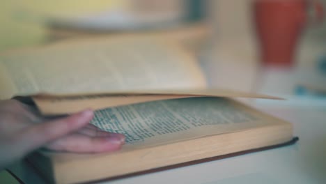 schoolkid turns yellow pages of textbook at table close view