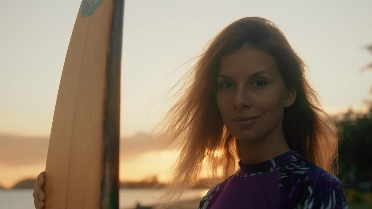 Woman with surfboard at sunset beach portrait