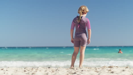 Niña-De-Pie-Relajada-En-La-Playa-Junto-Al-Mar