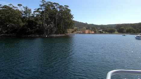 llegando al sitio histórico de port arthur a través de un barco turístico con los antiguos edificios del asentamiento penal al fondo.