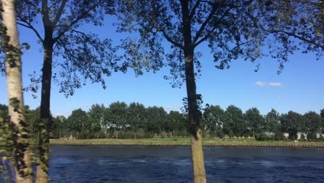 Following-part-of-the-Amsterdam-canal-in-The-Netherlands-with-a-ship-passing-on-the-waterway-staying-on-the-same-level-as-the-water