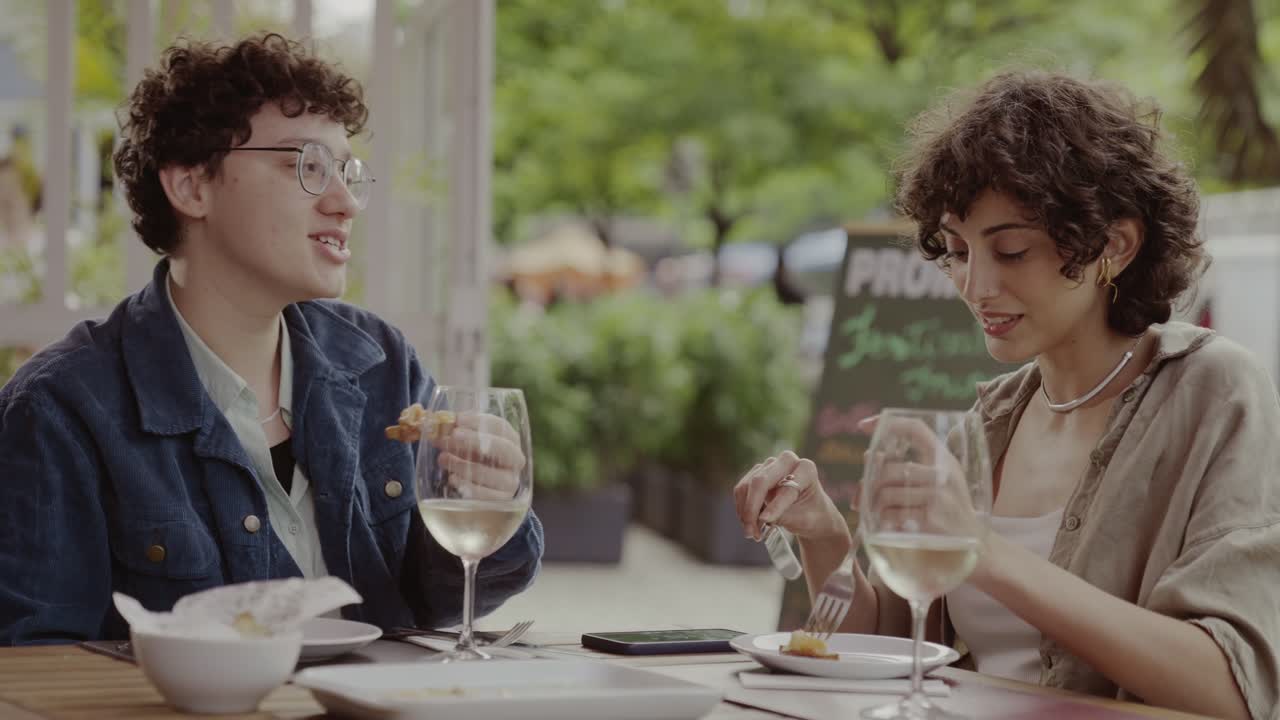 Two friends enjoying an outdoor meal at a restaurant