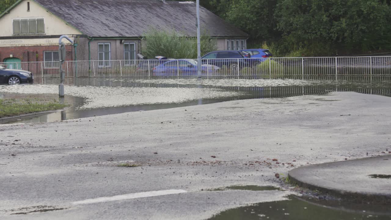 Flooded Roundabout with Debris Left in Road After Water Began Receding After Flash Flood with Submerged Car and Building