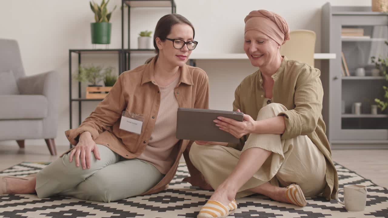 Donna con malattia oncologica che parla con un assistente sociale a casa