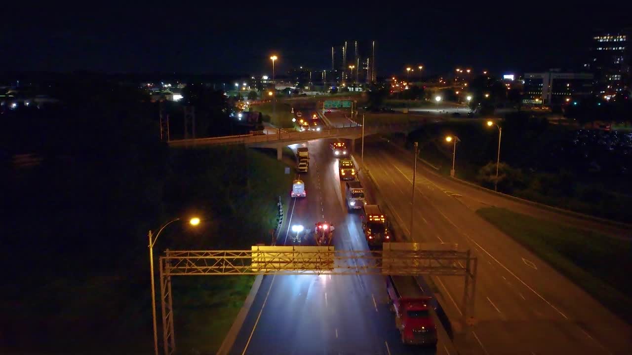 Drone push in view of highway blocked by fire trucks and other vehicles at night in Montreal, Quebec.