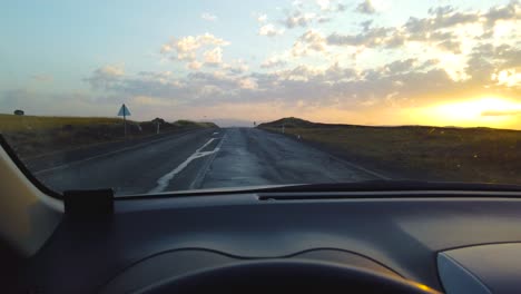 slow motion:view from inside car on empty hilly road leading to horizon line at sunset or sunrise