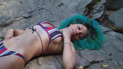 Bikini-woman-laying-on-a-rock-with-green-curly-hair-on-a-sunny-day-in-the-Caribbean