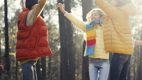 close-up view of joyful kids, girl and two boys, laughing, jumping and having fun in the forest on a sunny day