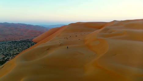 vista aérea de un hombre caminando solo en la parte superior de las dunas, u.a.e.