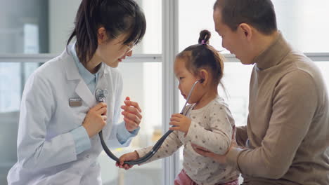 asian female pediatrician playing with toddler girl on checkup