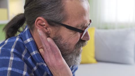 Close-up-shot-of-old-man-with-sore-ears-at-home.-Disease.