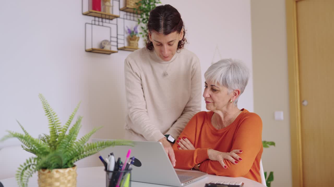 Young Woman Helps Senior Woman Learn to Use Laptop at Home