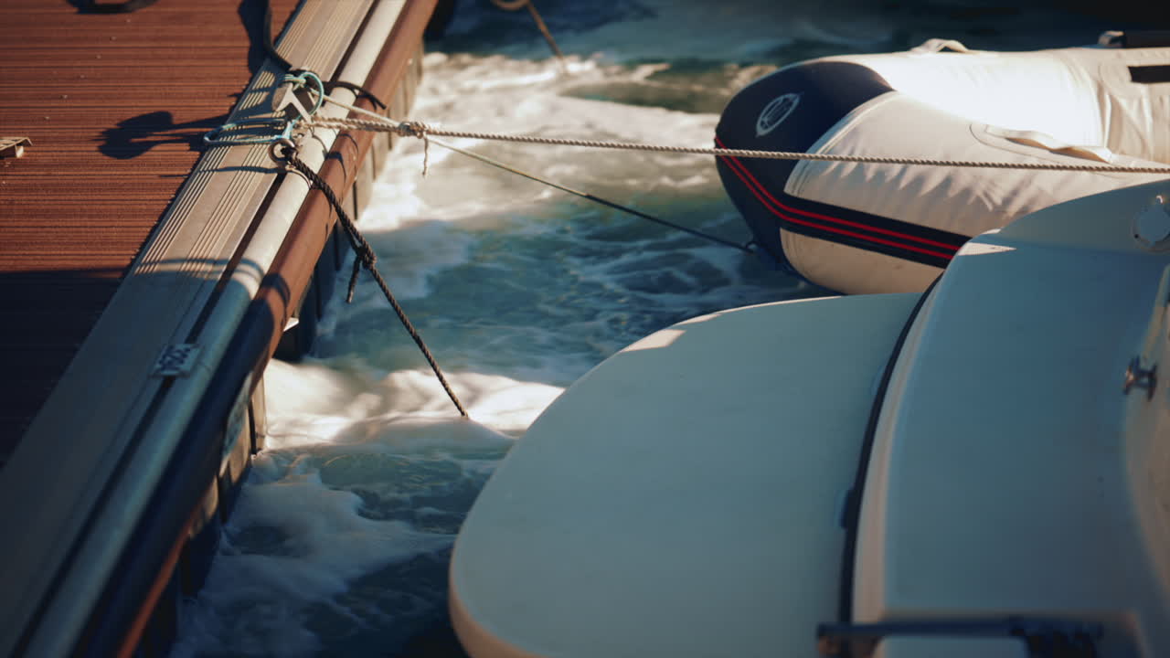 Close up of ropes tied to a wooden dock as water splashes below