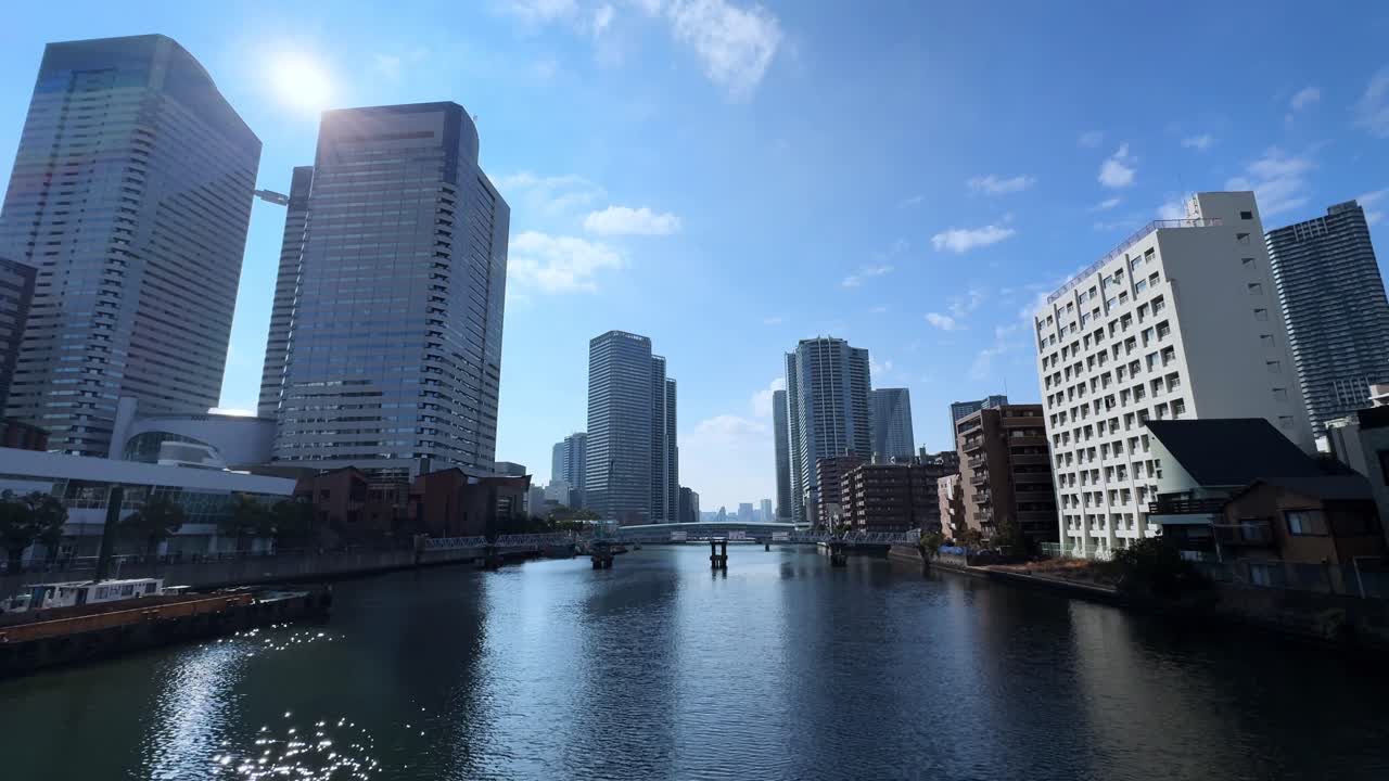 A sunny cityscape with modern skyscrapers along a canal in Harumi, Tokyo