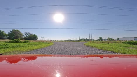 POV-Beim-Fahren-Eines-Roten-Fahrzeugs-Auf-Einer-Schotterstraße-In-Richtung-Einer-Kreisstraße