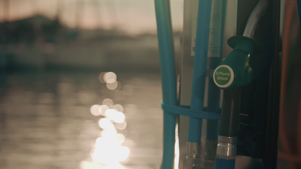 Close up of a marine fuel pump at a harbor during sunset, with warm bokeh reflections on the water and a calm nautical atmosphere